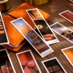 Bookmark in hình đang đặt bên sổ da cam, ánh sáng vàng dịu.